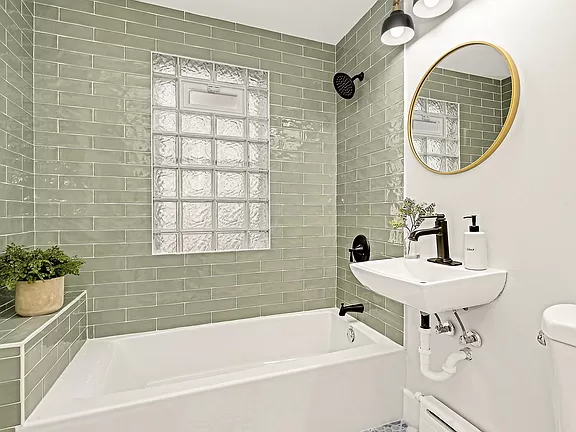 Luxurious marble-tiled bathroom featuring a freestanding bathtub and large window.